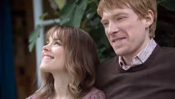 Tim (Domhnall Gleeson) and Mary (Rachel McAdams) smile while sitting together outdoors