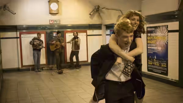 Tim (Domhnall Gleeson) carries Mary (Rachel McAdams) piggyback through an underground station
