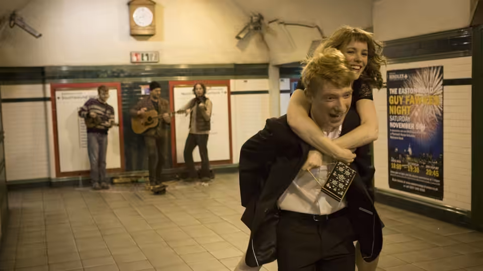 Tim (Domhnall Gleeson) carries Mary (Rachel McAdams) piggyback through an underground station