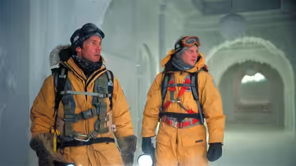 Jack Hall (Dennis Quaid) and a colleague in yellow parkas inside an icy corridor