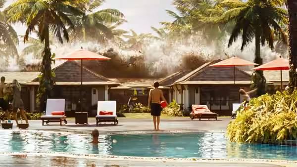 A resort guest stands by the pool as a massive wave approaches