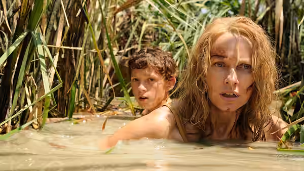 Maria Bennett (Naomi Watts) and Lucas Bennett (Tom Holland) wade through flooded reeds