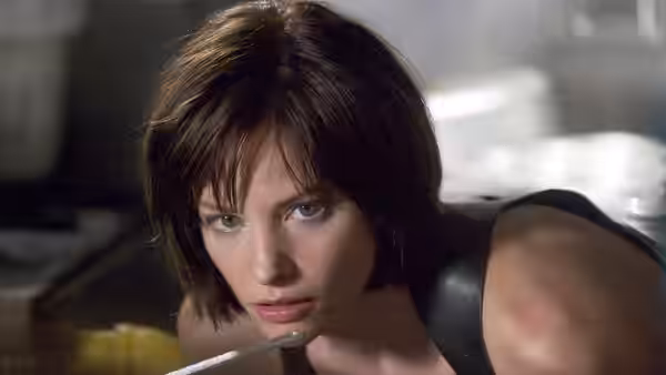Alice (Milla Jovovich) holding a syringe near her face