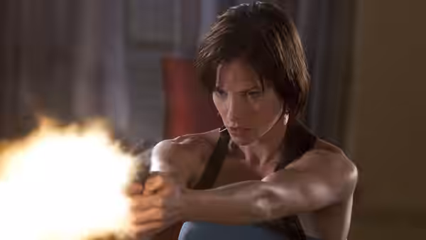 Alice (Milla Jovovich) firing a handgun with bright muzzle flash