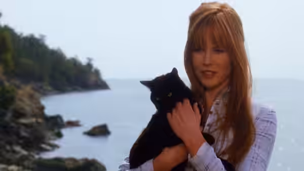Sally Owens (Sandra Bullock) holding a black cat by the ocean