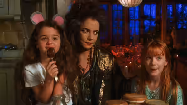 A woman and two girls sitting at a table with food and drinks