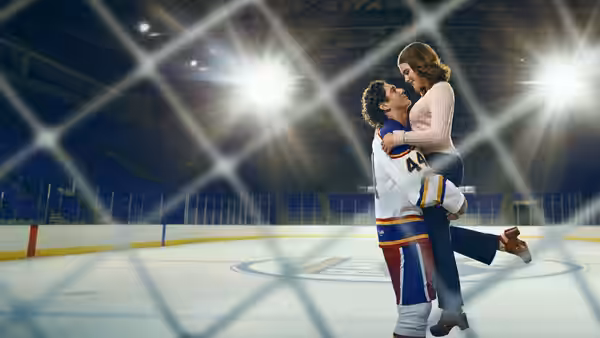 Hockey player lifts woman in his arms on an ice rink