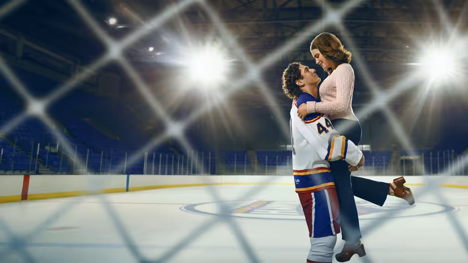 Hockey player lifts woman in his arms on an ice rink