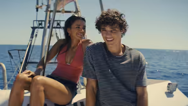 Oriah (Maia Reficco) and Julián (Fernando Lindez) smiling on a boat at sea