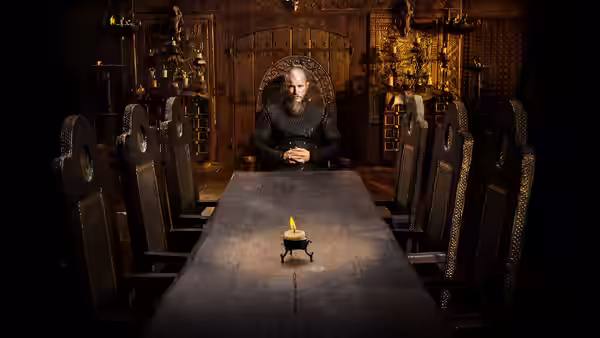 Ragnar Lothbrok (Travis Fimmel) alone at a candlelit table in a hall