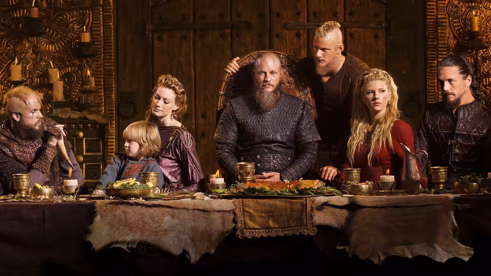 Vikings gathered around a long feast table in a wooden hall