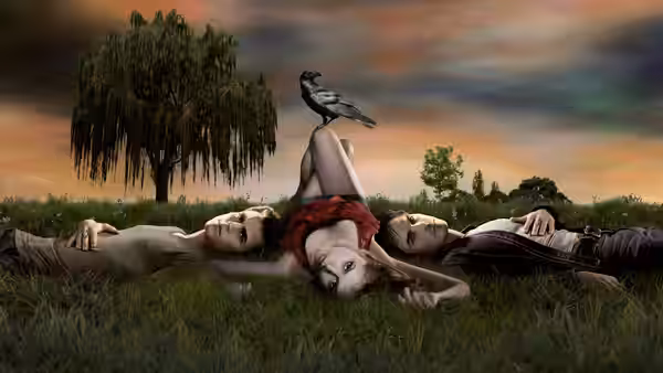 Four people lie on grass under a tree with a crow perched on one