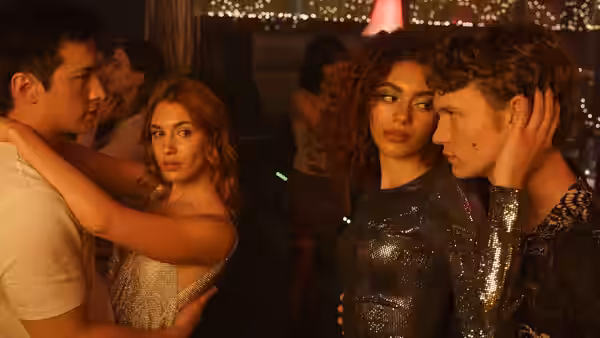 Four people interact closely at a crowded nighttime party