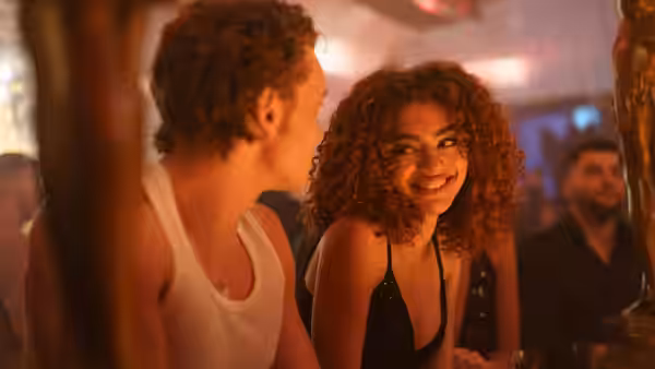 Ilya Rozanov smiles at a woman with curly red hair in a club