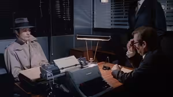 Jef Costello (Alain Delon) sits across a desk from an official in an office