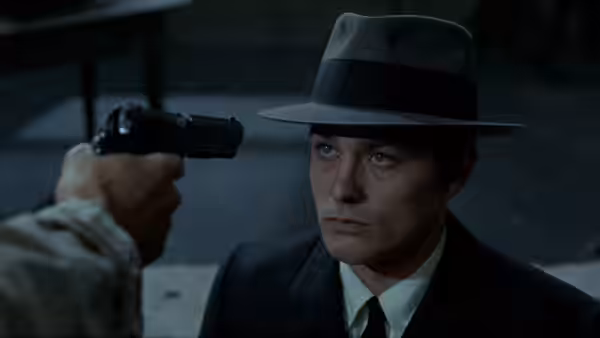 Jef Costello (Alain Delon) faces a pistol aimed at him from offscreen