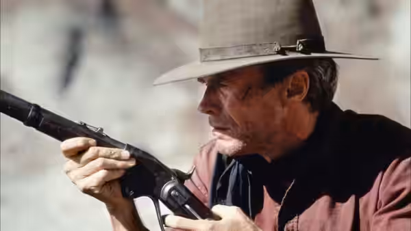 William Munny (Clint Eastwood) holding a rifle and looking to his left