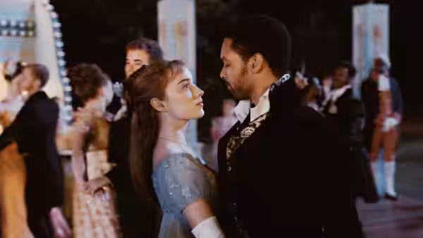 A red-haired woman in blue stares at a man in a black embroidered coat