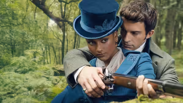 A woman in a blue hat aims a rifle in a forest with a man behind her