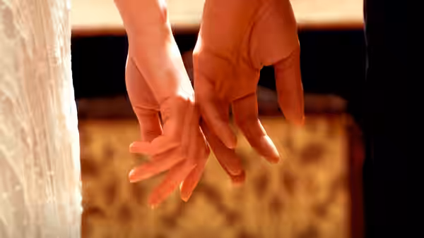 Two hands reach toward each other with fingers almost touching in soft light