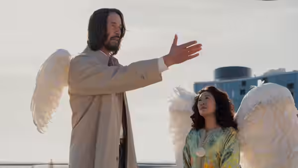 Gabriel (Keanu Reeves) gesturing beside a winged woman on an overcast rooftop
