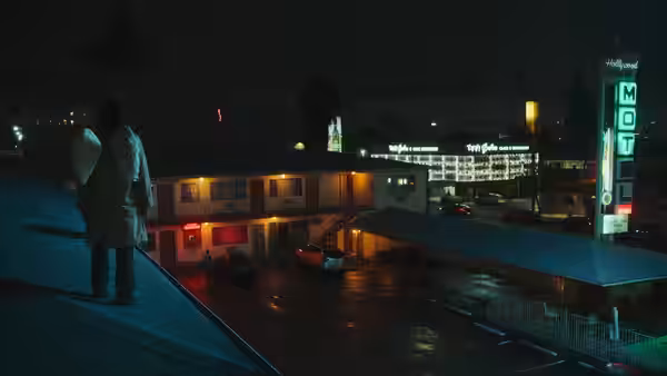 Gabriel (Keanu Reeves) standing on a rooftop overlooking a neon-lit motel at night
