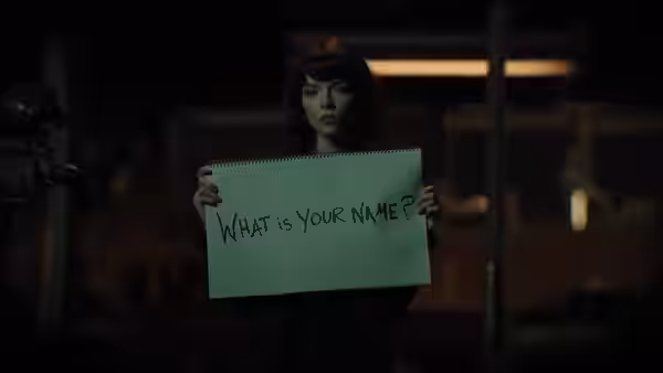 Drasa (Anya Taylor-Joy) holding a notepad reading what is your name