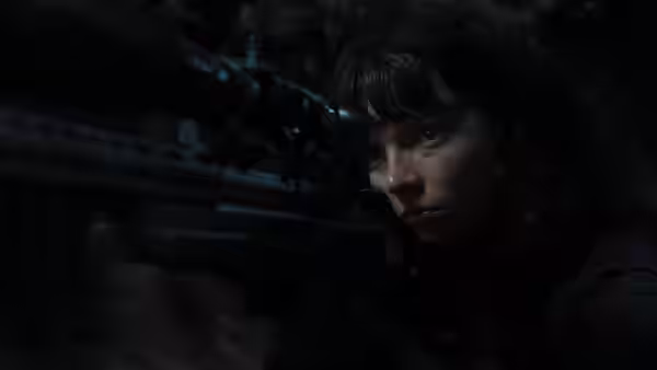 Drasa (Anya Taylor-Joy) aiming a scoped rifle in darkness