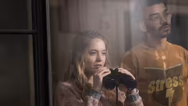 Pippa (Sydney Sweeney) holding binoculars beside Thomas (Justice Smith) at the window