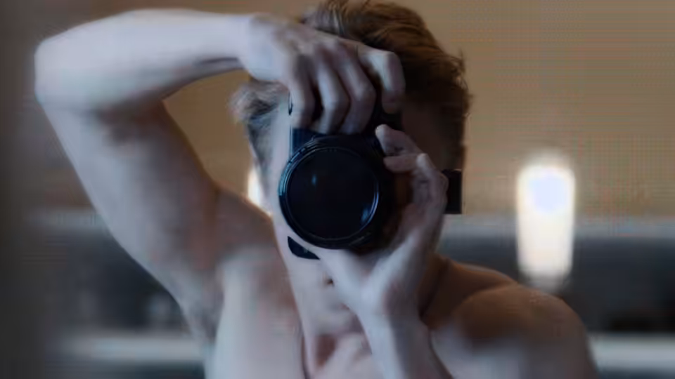 Seb (Ben Hardy) photographing with a camera held to his face