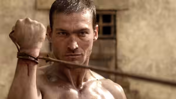 Spartacus (Andy Whitfield), bound and shirtless, stares defiantly with rope around his neck