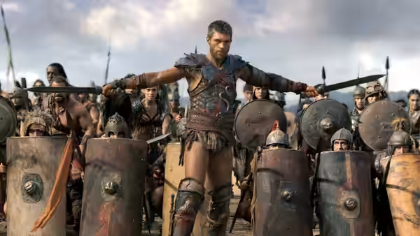 Spartacus (Andy Whitfield) stands with arms outstretched among his armed warriors