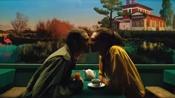 Murphy (Karl Glusman) and Omi (Klara Kristin) kissing on a boat with painted backdrop