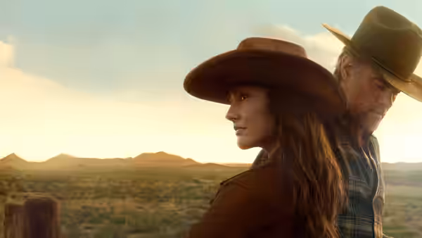 Woman and man in cowboy hats standing together at sunset overlooking hills
