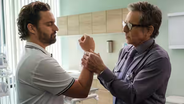 Ben Stiller examining Jake Johnson's arm in a medical office