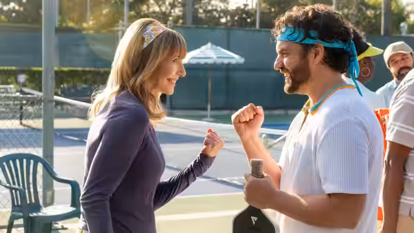 Mary Steenburgen and Jake Johnson fist-bumping on a tennis court