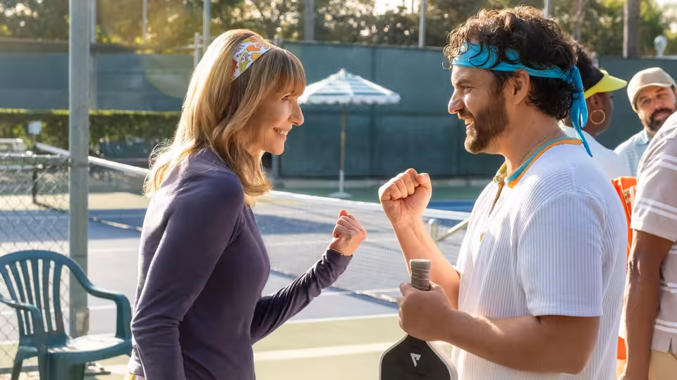 Mary Steenburgen and Jake Johnson fist-bumping on a tennis court