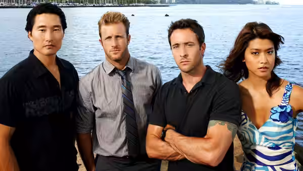 Four people pose together by the water with a city skyline behind them