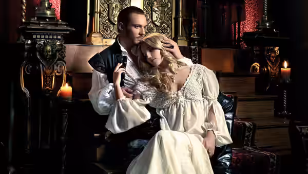 Henry VIII (Jonathan Rhys Meyers) cradles a blonde woman on a carved chair