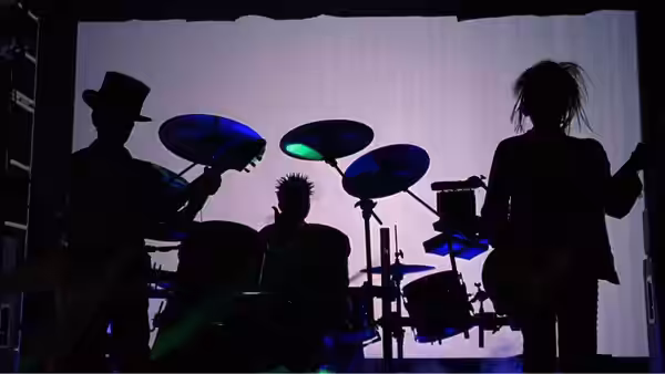 Silhouetted rock band performing on stage under blue lights