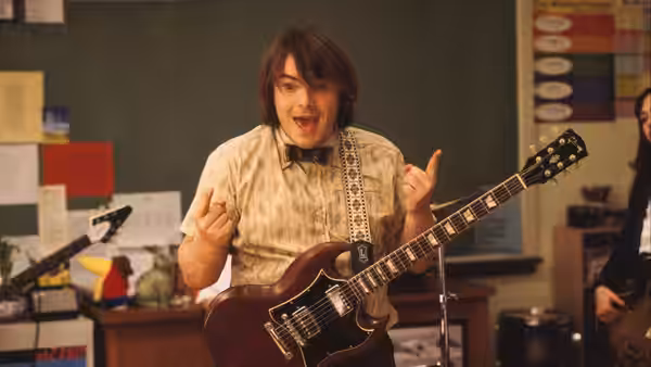 Dewey Finn (Jack Black) playing electric guitar in a classroom