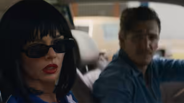 A woman in sunglasses sits beside a man driving a car at dusk