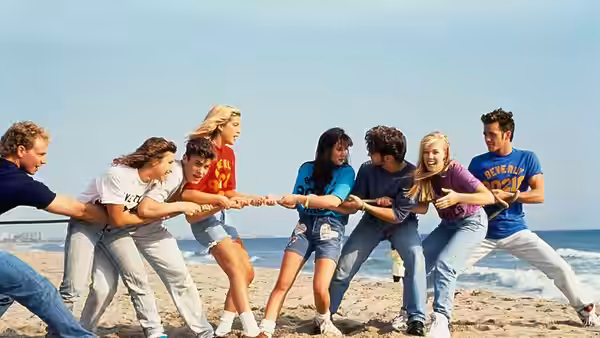 Group of young people playing tug of war on the beach