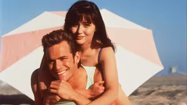 Man and woman posing together under a beach umbrella