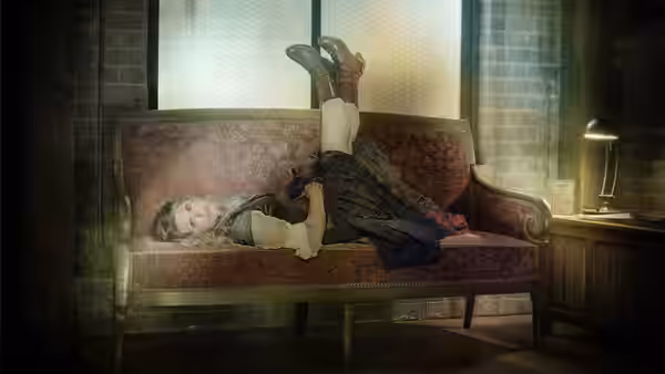A young woman reclining upside down on a red patterned couch