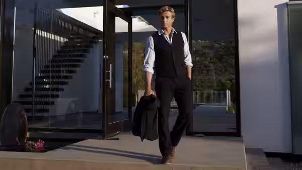 Patrick Jane (Simon Baker) walks out of a modern building with his jacket