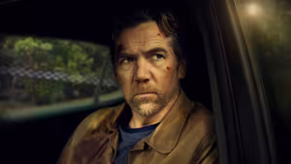 A bruised man sits in the driver's seat of a vehicle