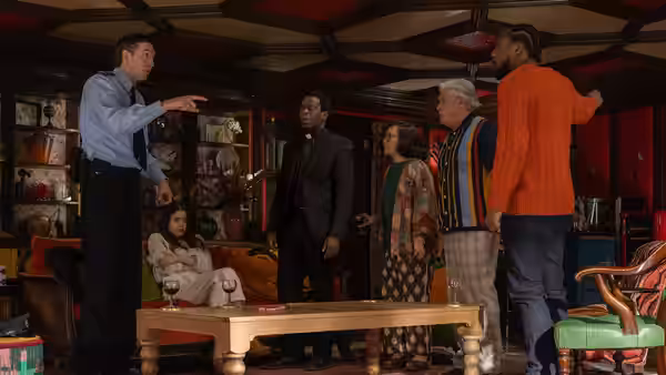 Officer Tim Derry (Nicholas Braun) points at a group inside a living room