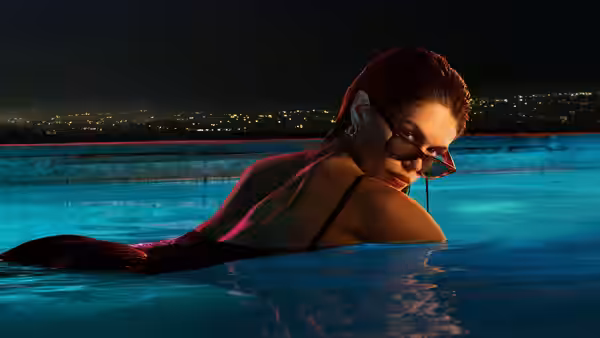 Woman in sunglasses floating on her back in a pool at night