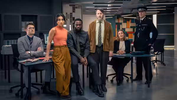 John Taylor (David Mitchell) with five colleagues in a modern office